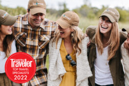 Four Knowmad Adventures team members in Knowmad hats walking and laughing together with a Condé Nast Traveler 2022 seal on the lower left.