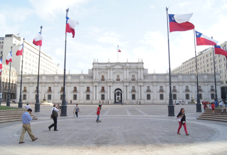 Chilean flags wave in from of the Chilean presidential palace in Santiago, Chile. Learn what to do in Santiago, Chile in 48 hours with Knowmad Adventures.