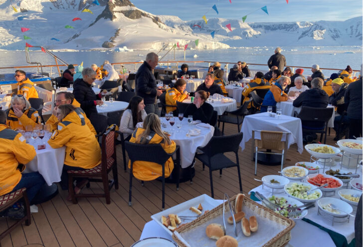 Travelers eating outside during their Antarctica expedition with Knowmad Adventures. 