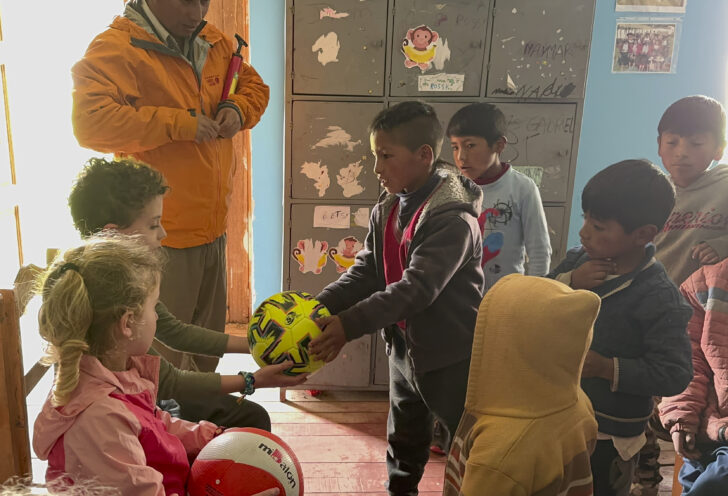 Children giving sports equipment to other children.