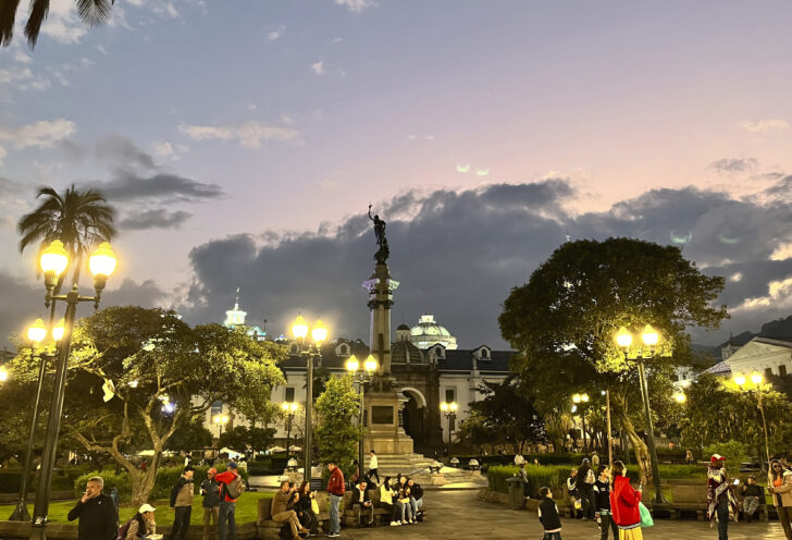 People gather at night under city lights in Quito, Ecuador.